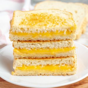 Stack of grilled cheese sandwiches on a plate.