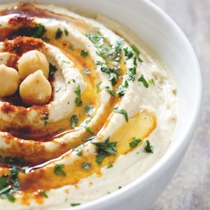 Bowl of hummus topped with parsley and oil.