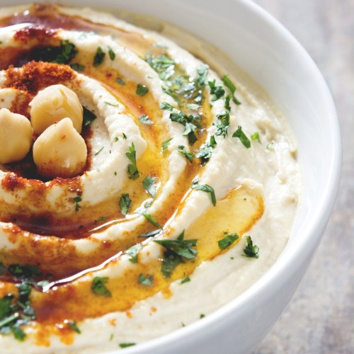 Bowl of hummus topped with parsley and oil.